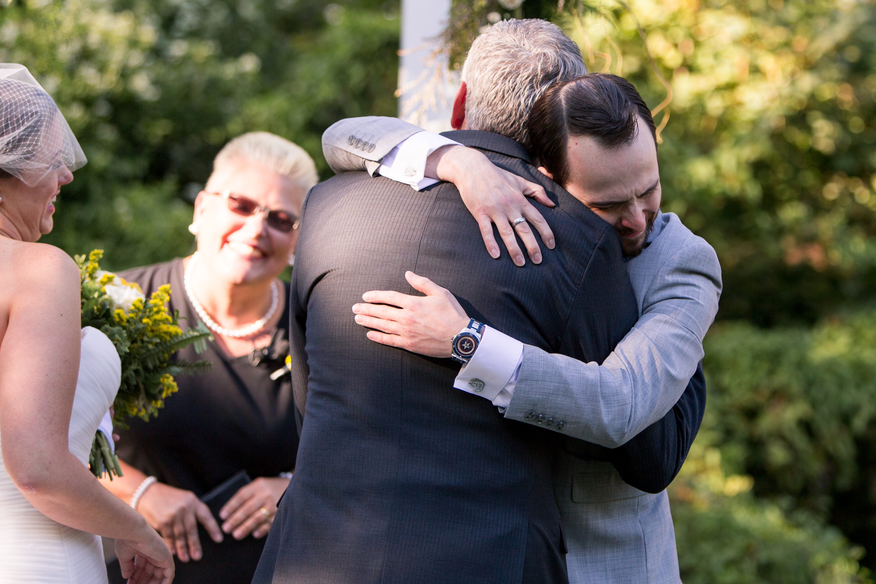 groom hugs father of bride during wedding ceremony at Minnetrista in Muncie Indiana