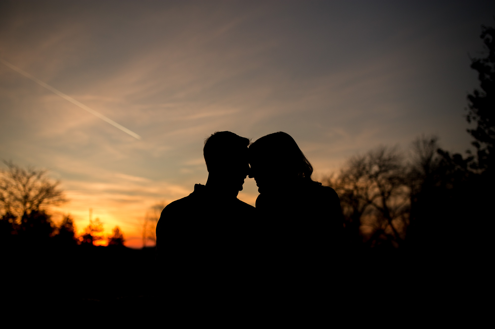 bride and groom silhouette sitting on hay bales during Eaton Indiana engagement session