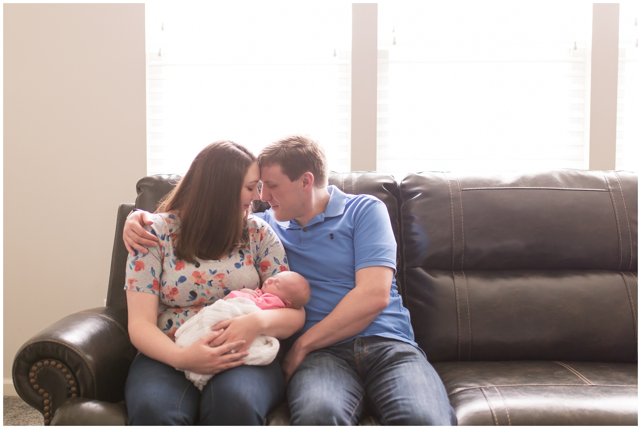 mom and dad on couch holding baby during Indianapolis newborn photography session