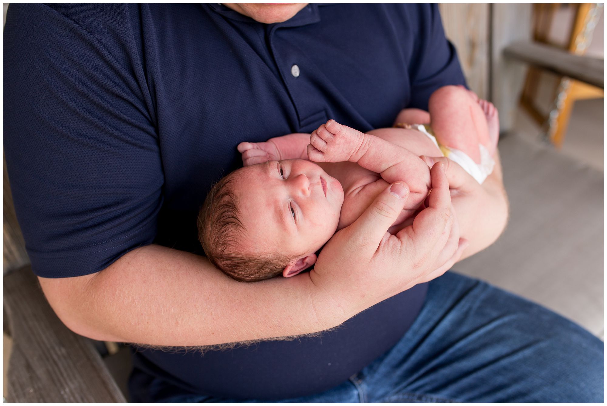 dad holds baby in arms during newborn session in Kokomo Indiana