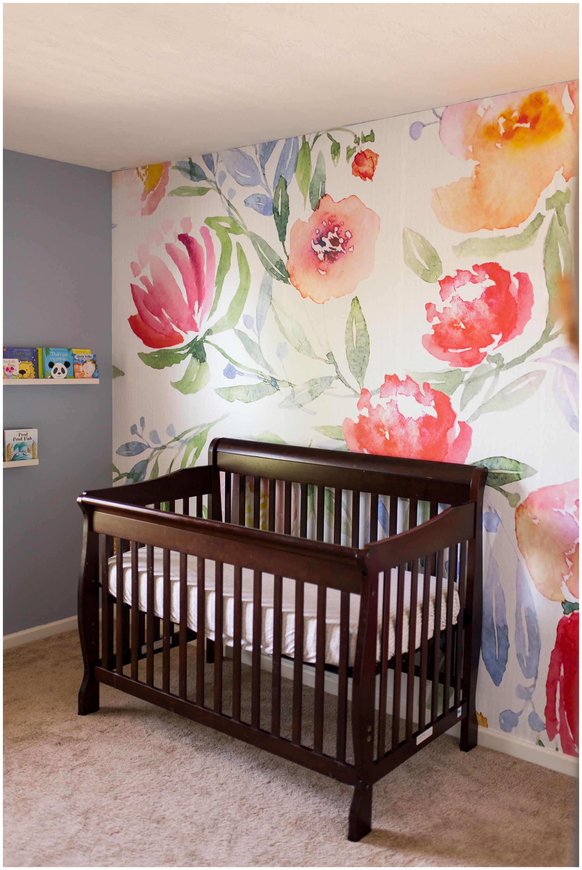 baby nursery details with flower wallpaper and crib