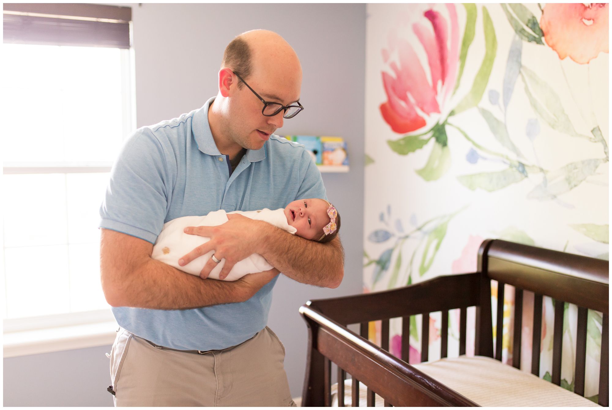 dad swaddles newborn baby in Westfield Indiana nursery during photo session