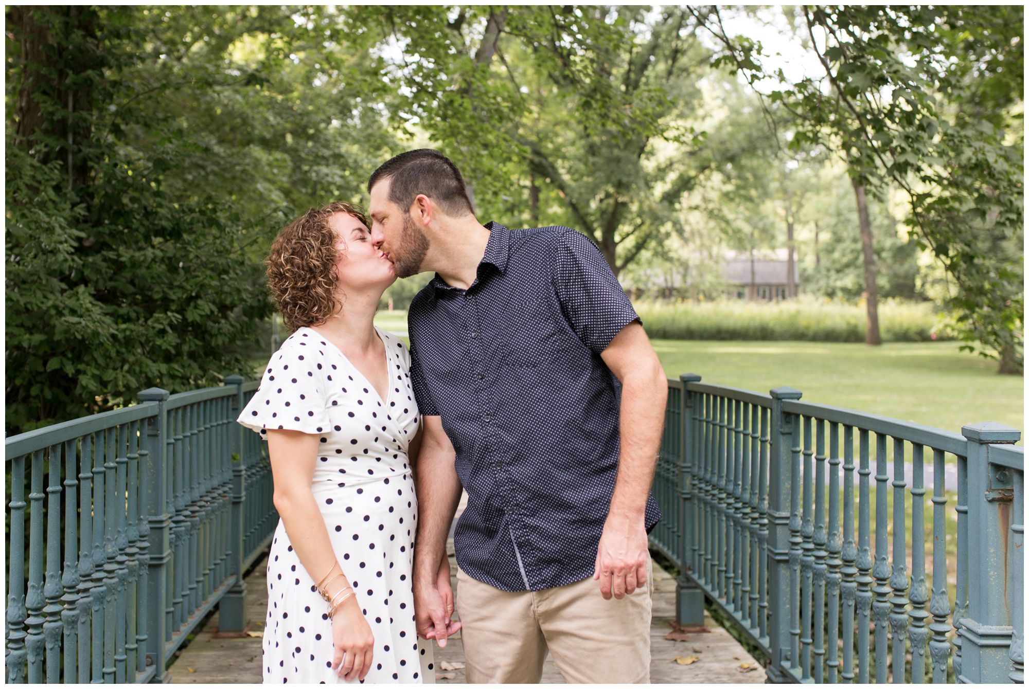bride and groom kissing on bridge during engagement session at Charley Creek Gardens in Wabash Indiana