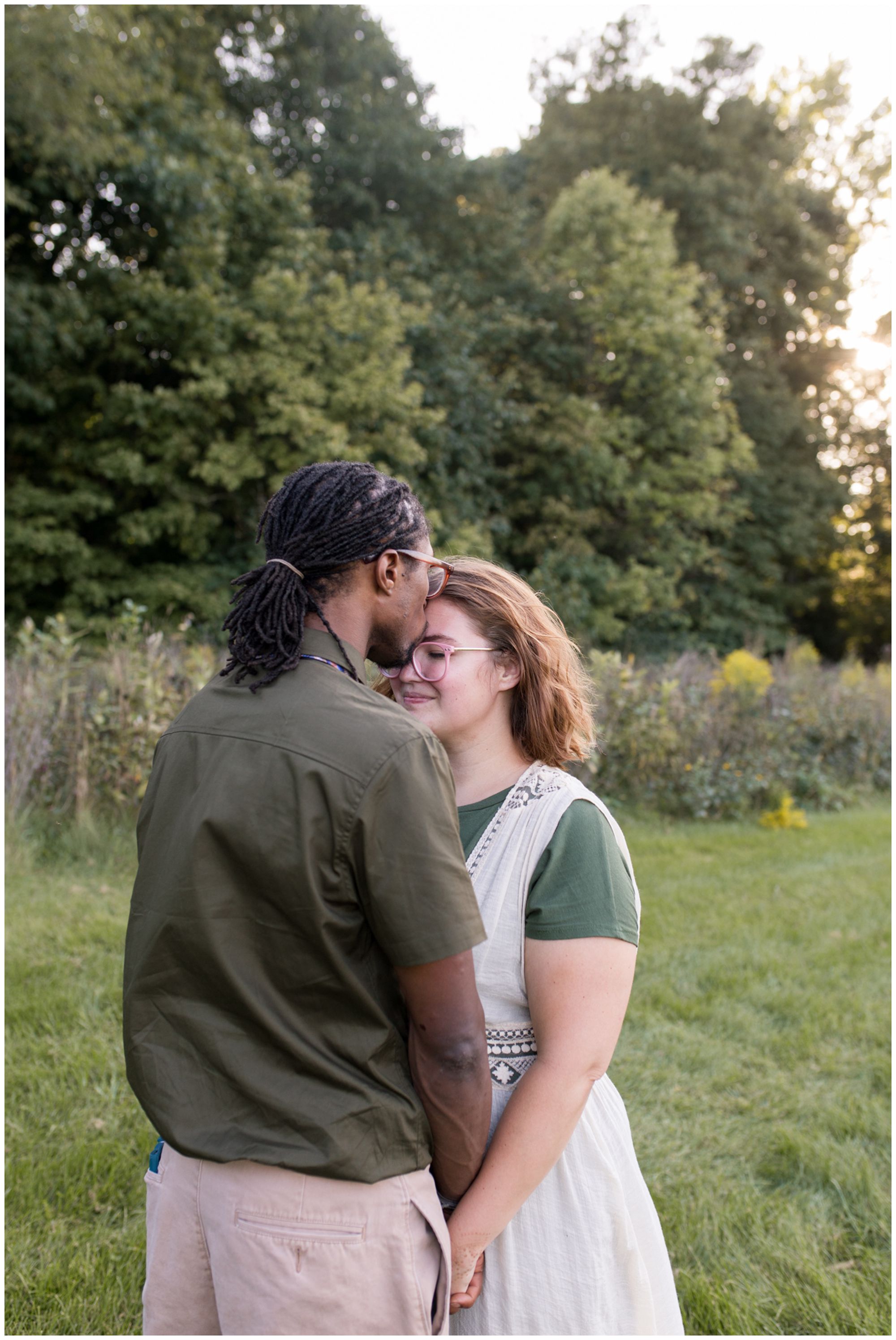 husband kisses wife's forehead during Kokomo family session at Jackson Morrow Park
