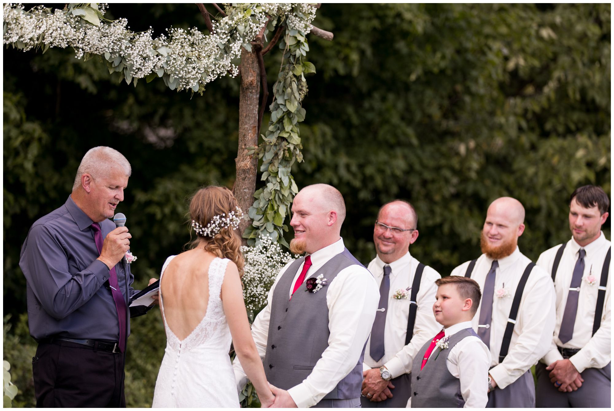 groom Daniel looks at bride Tabea during wedding ceremony with groomsmen looking on behind Daniel