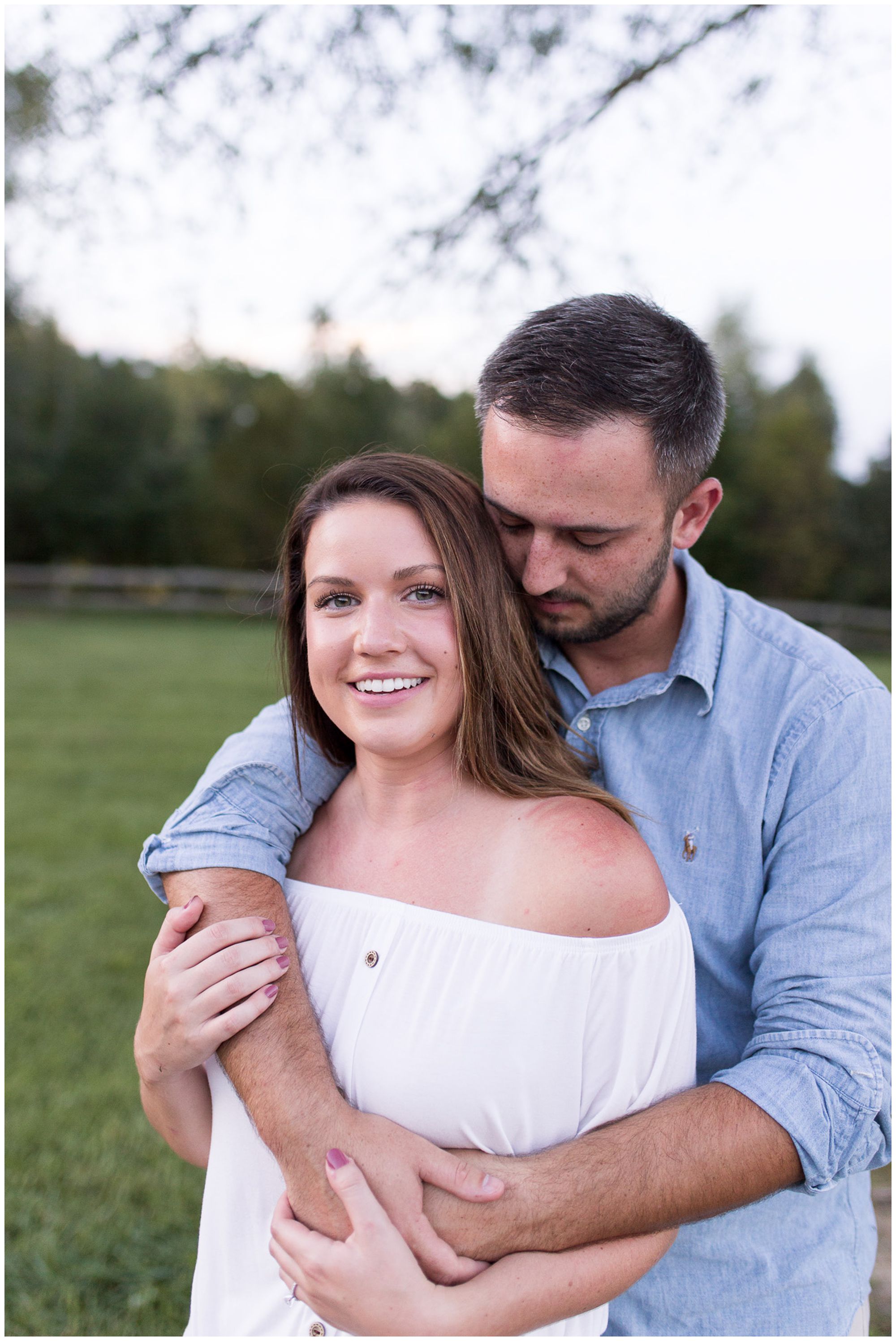 groom hugs bride from behind during Metea County Park engagement session in Fort Wayne Indiana