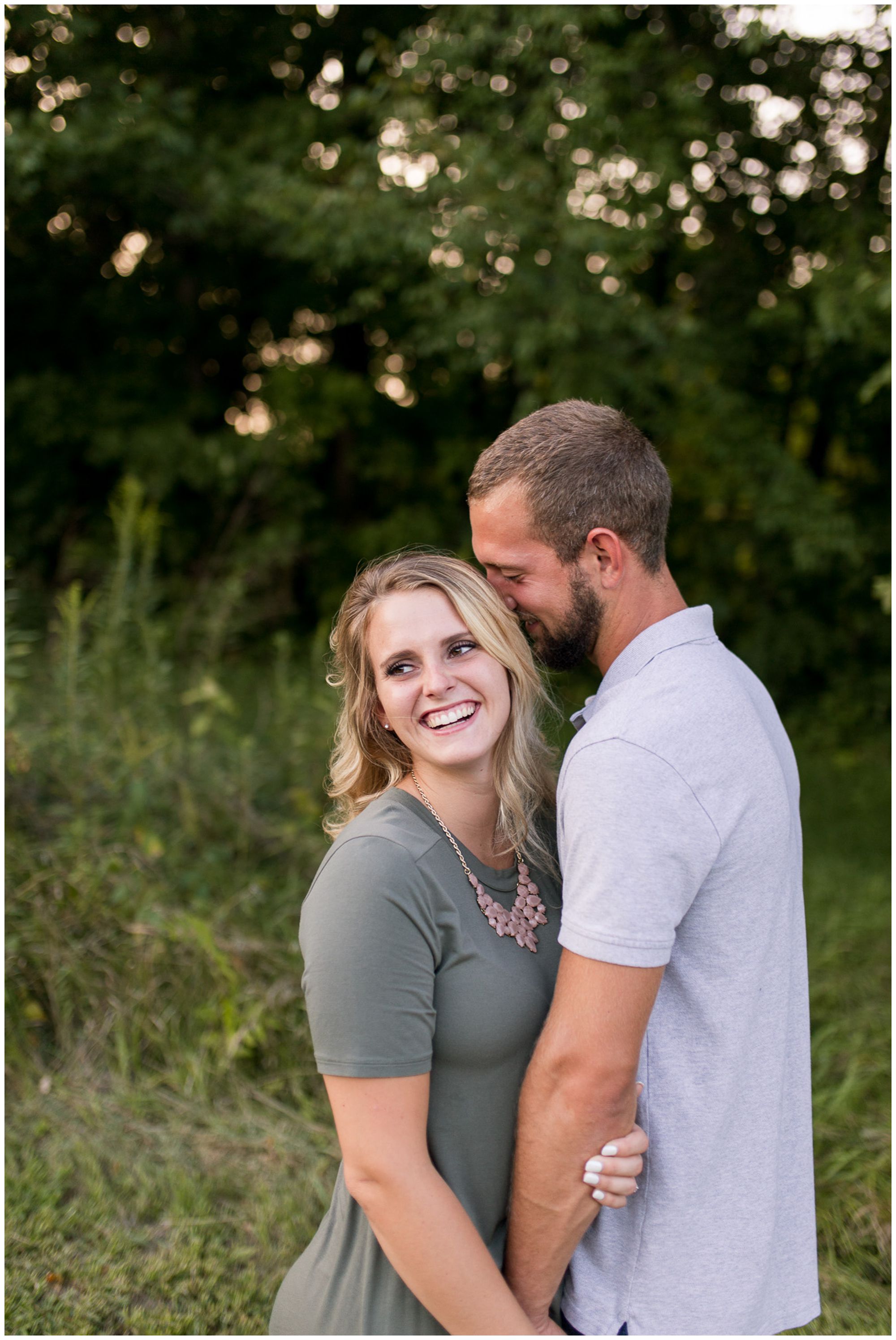 bride laughs while groom whispers in her ear during engagement session at Metea County Park in Fort Wayne