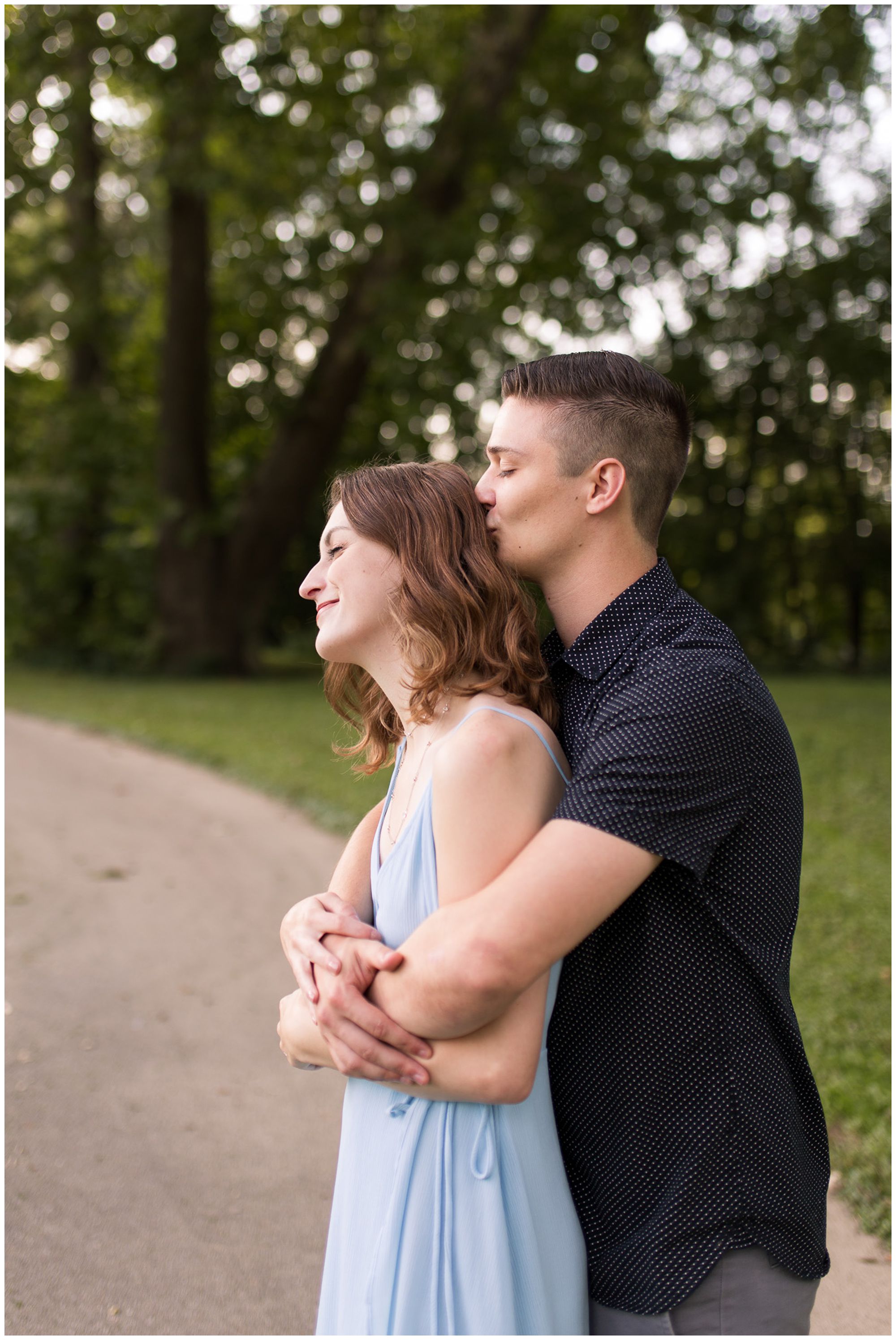 groom kisses bride's hair during Fort Wayne engagement session at Foster Park