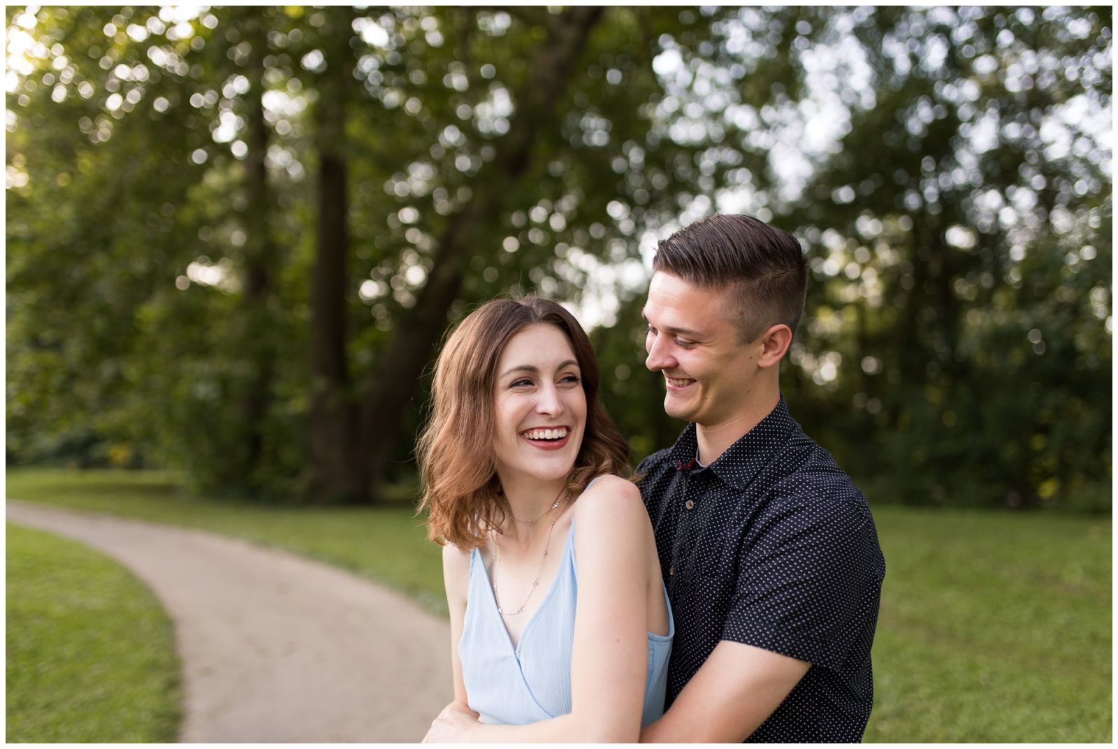 bride looks back and laughs with groom during engagement session at Fort Wayne's Foster Park