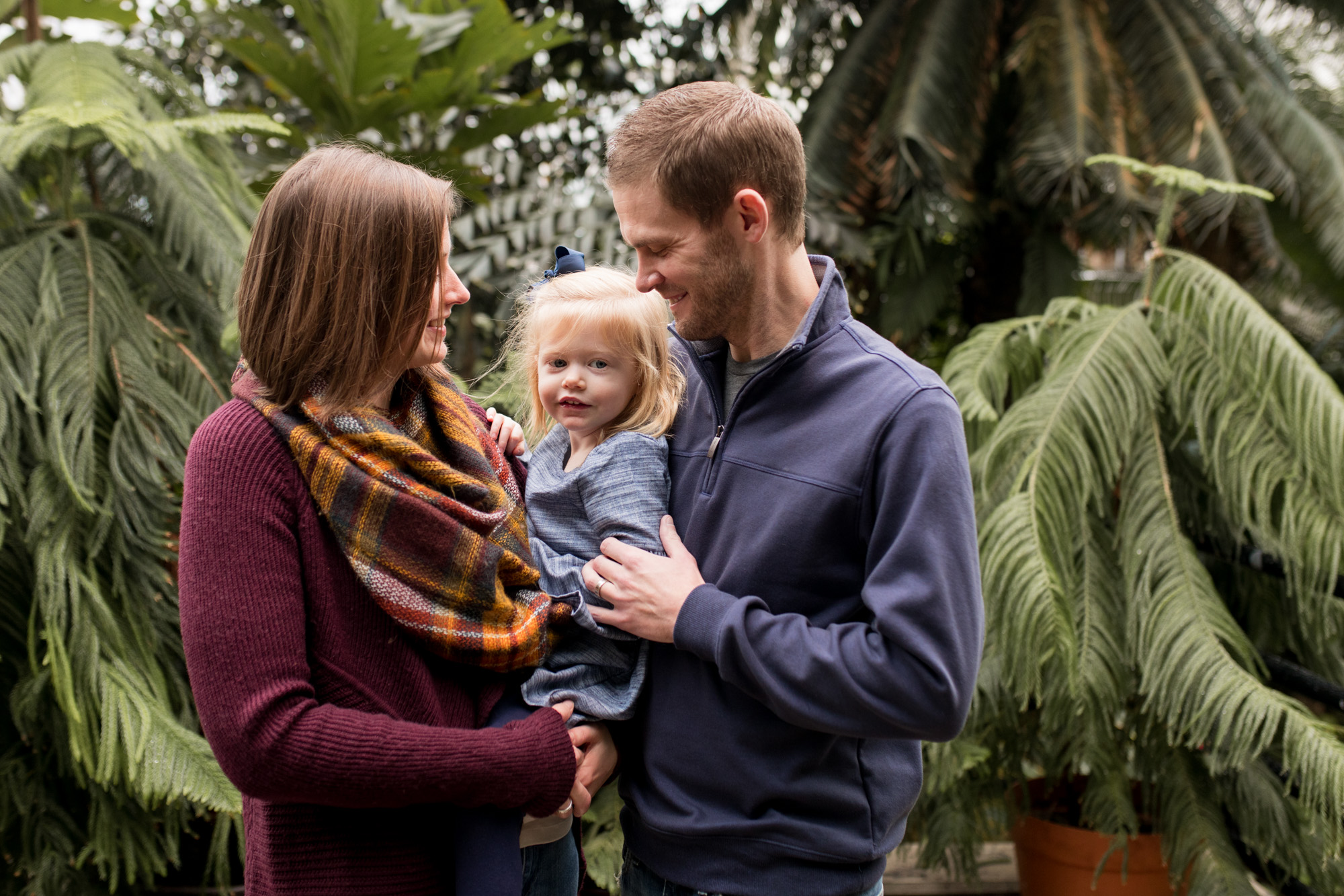 mom and dad hold and look at baby during Foellinger-Freimann Botanical Conservatory family session in Fort Wayne Indiana