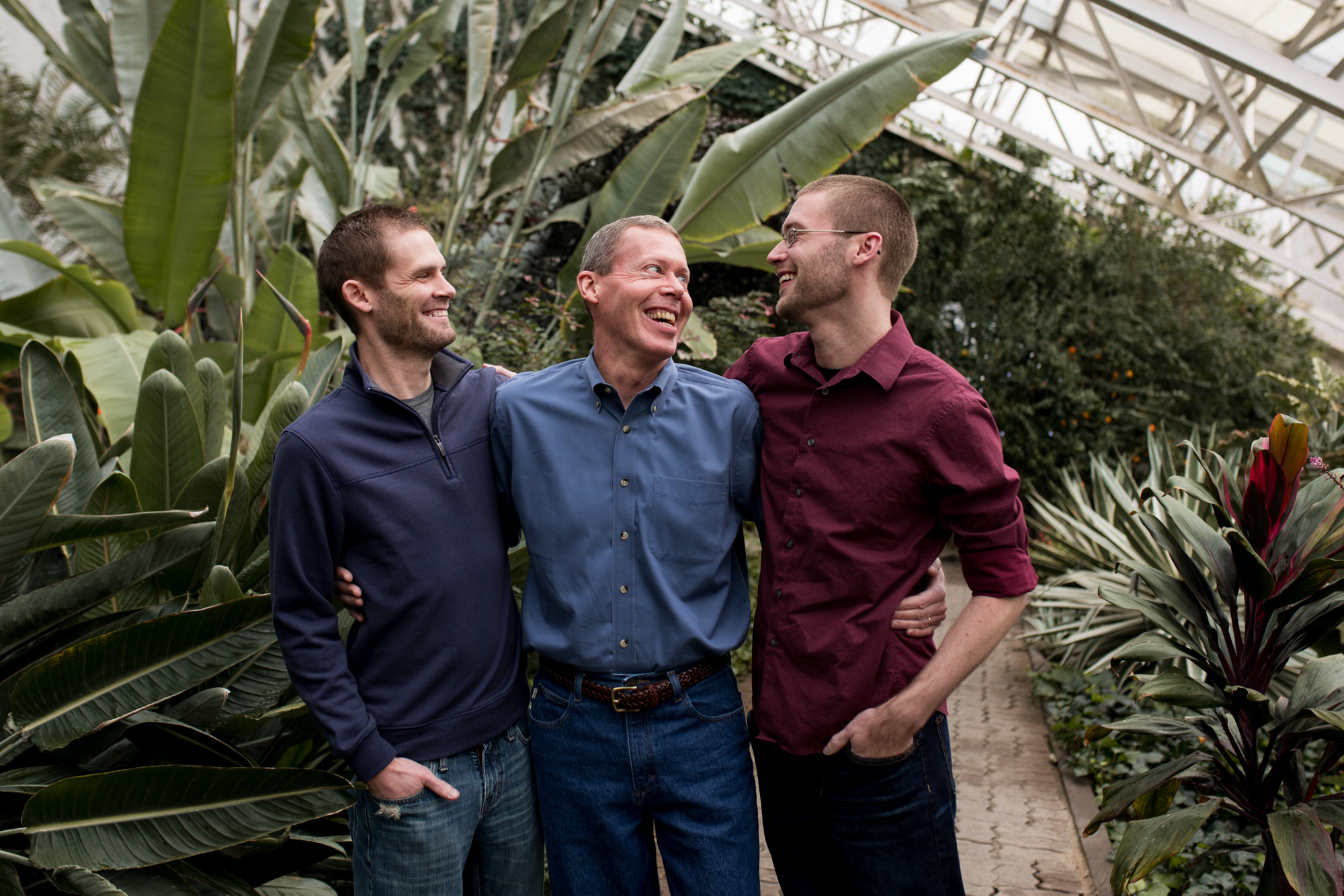 father and sons laugh together during family session at Foellinger-Freimann Botanical Conservatory in Fort Wayne Indiana