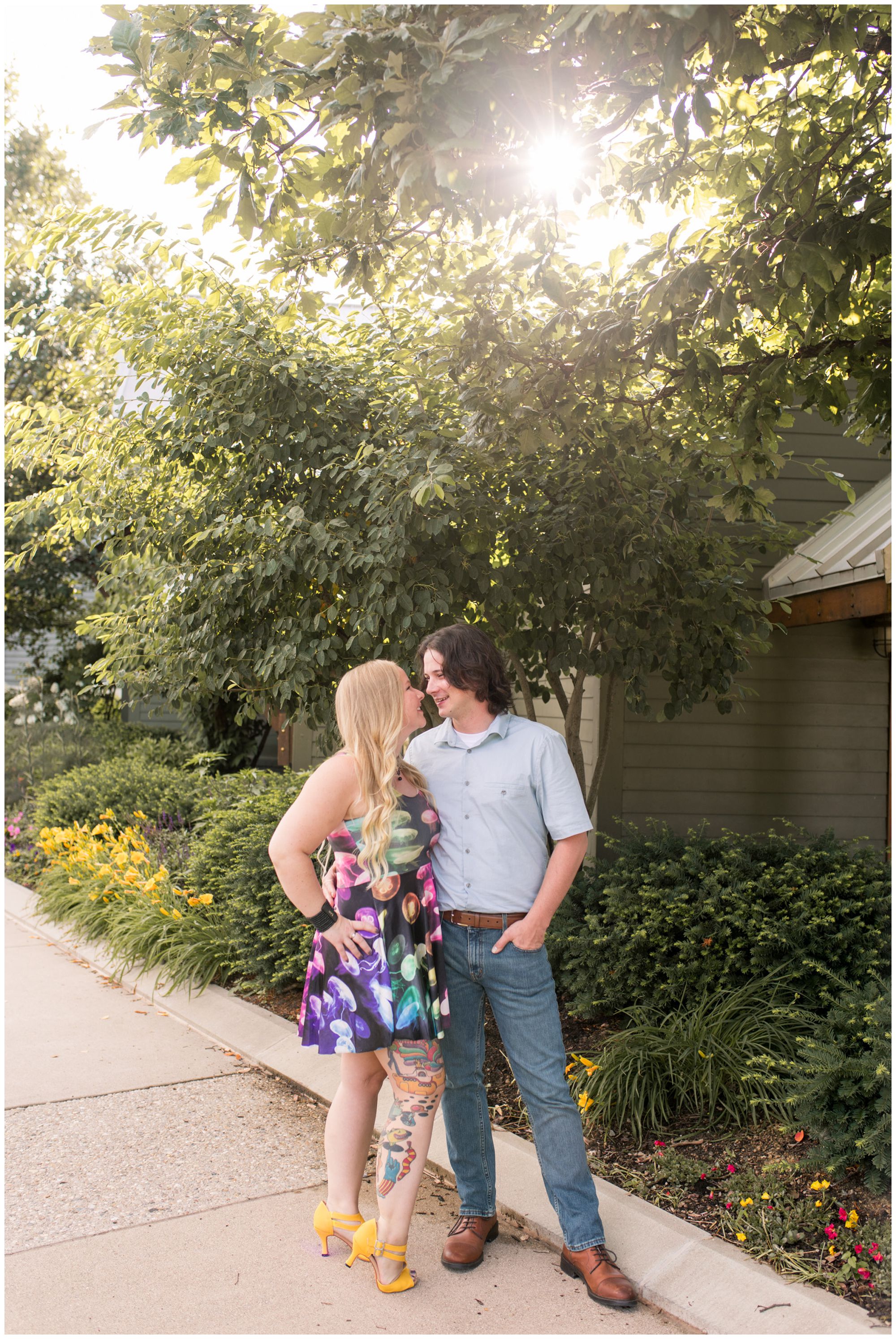 couple wrapping arms around each other during engagement session in Broad Ripple