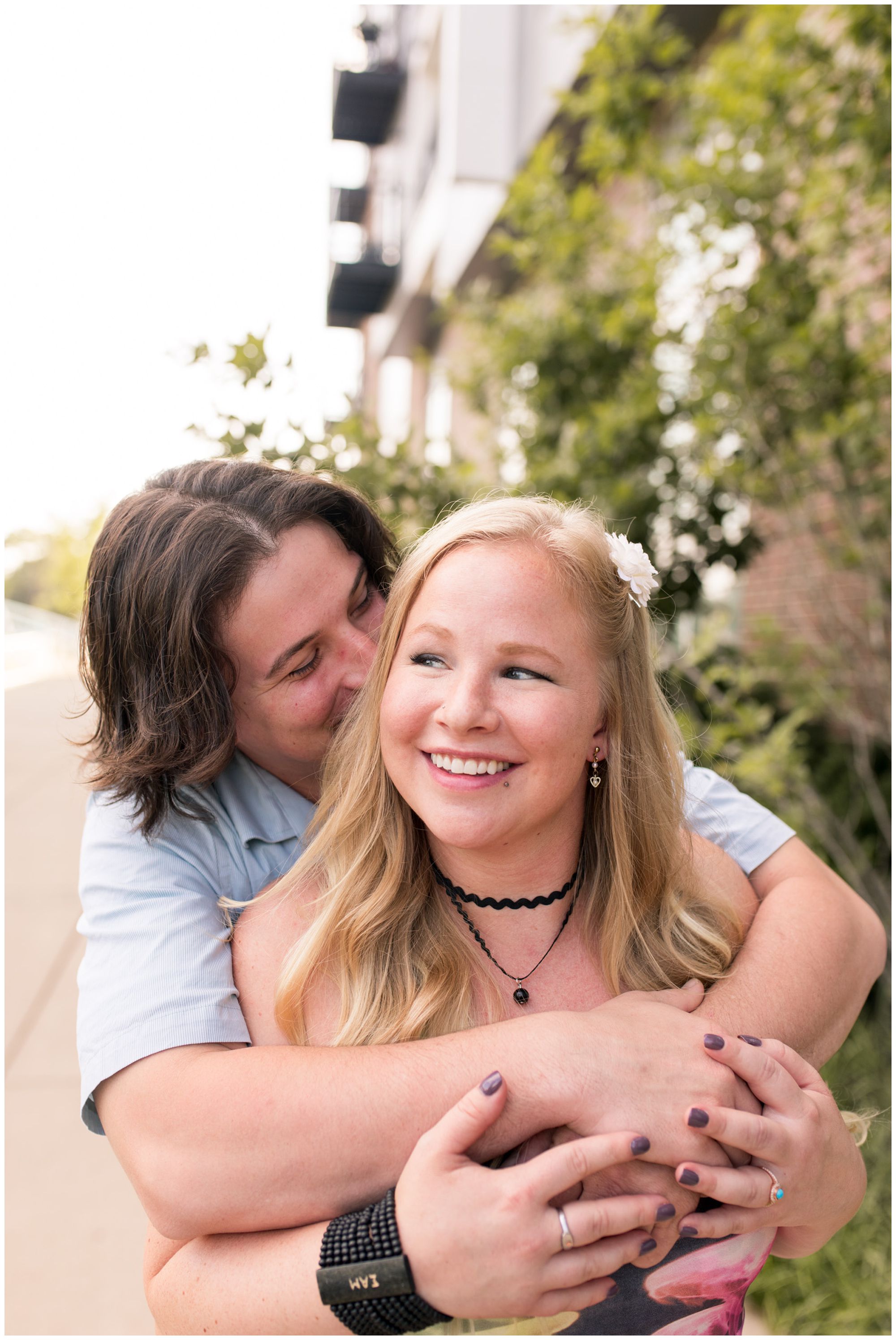 groom wraps arms around bride and whispers in her ear during Broad Ripple engagement session