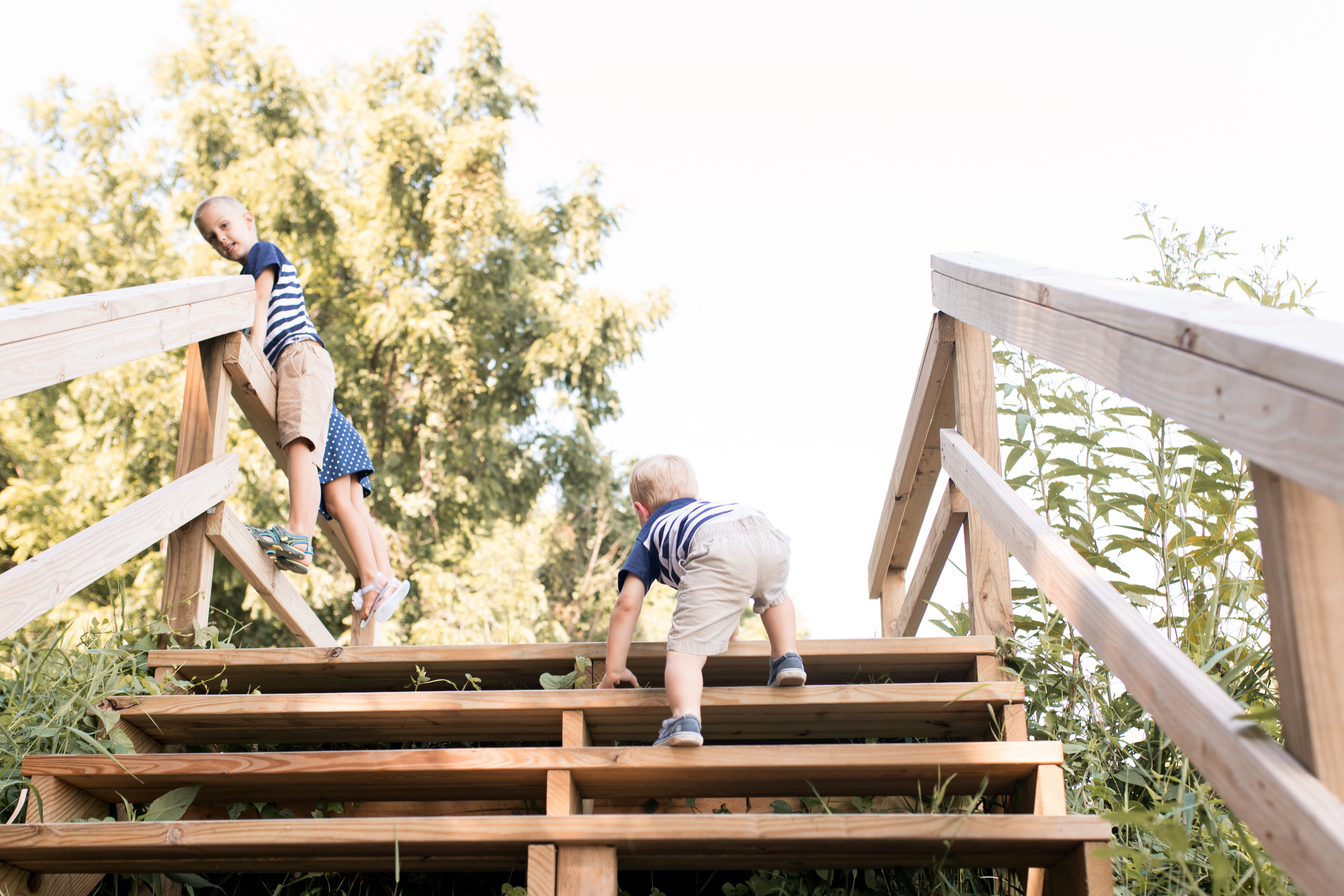 youngest brother climbs stairs to join siblings during family session at Potters Bridge Park in Noblesville Indiana