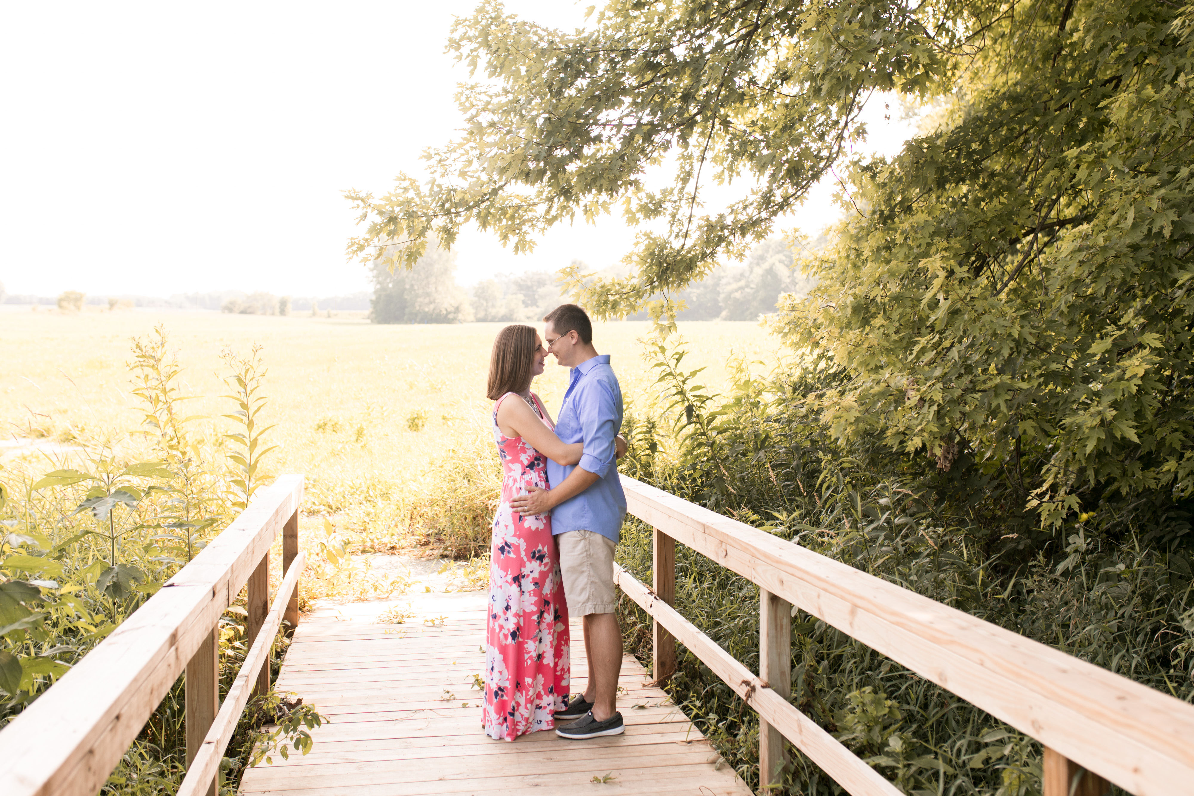 couple hugs on bridge during family session at Potters Bridge Park in Noblesville Indiana