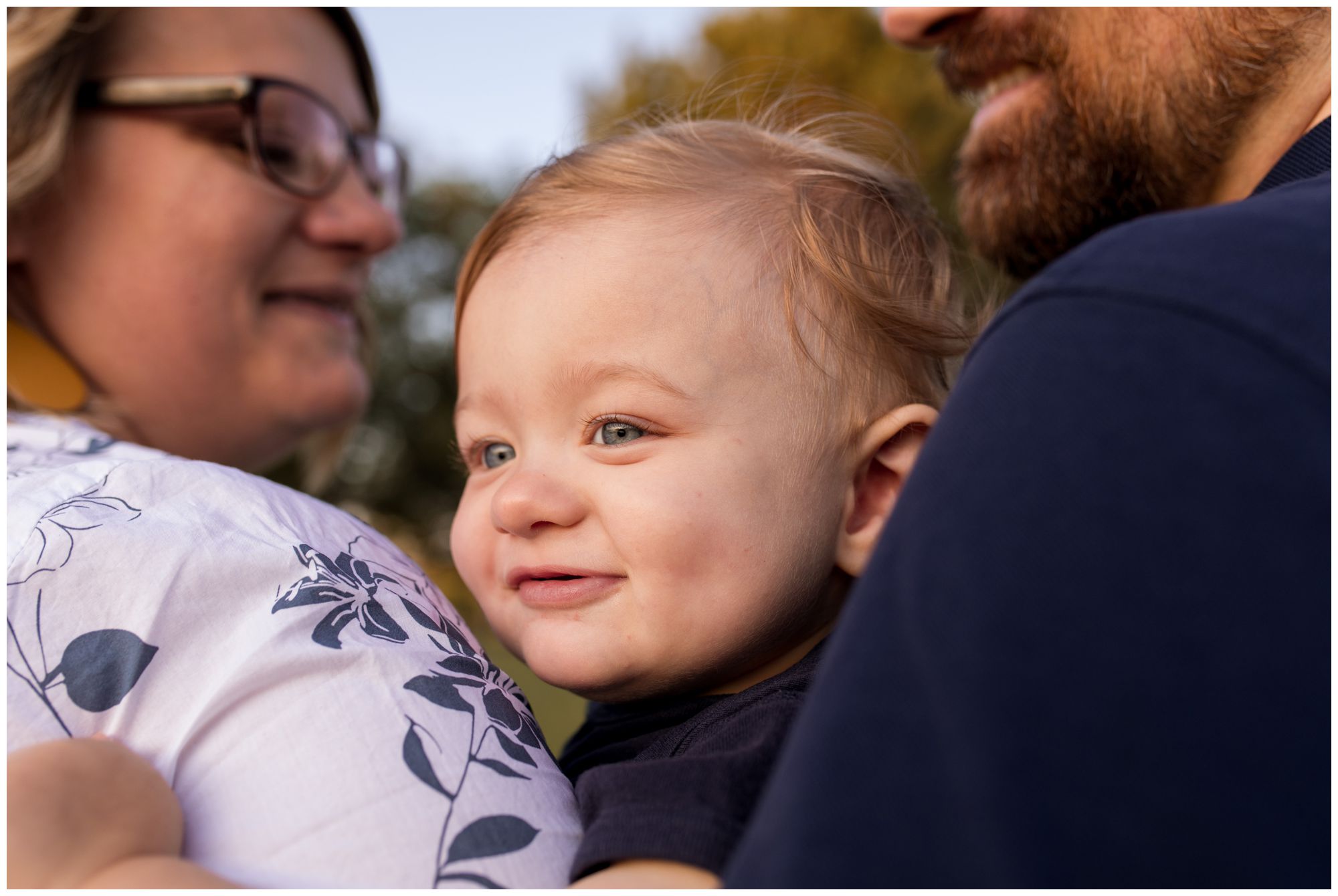 son sits between mom and dad during family session at Wildkat Creek Reservoir Park in Kokomo Indiana