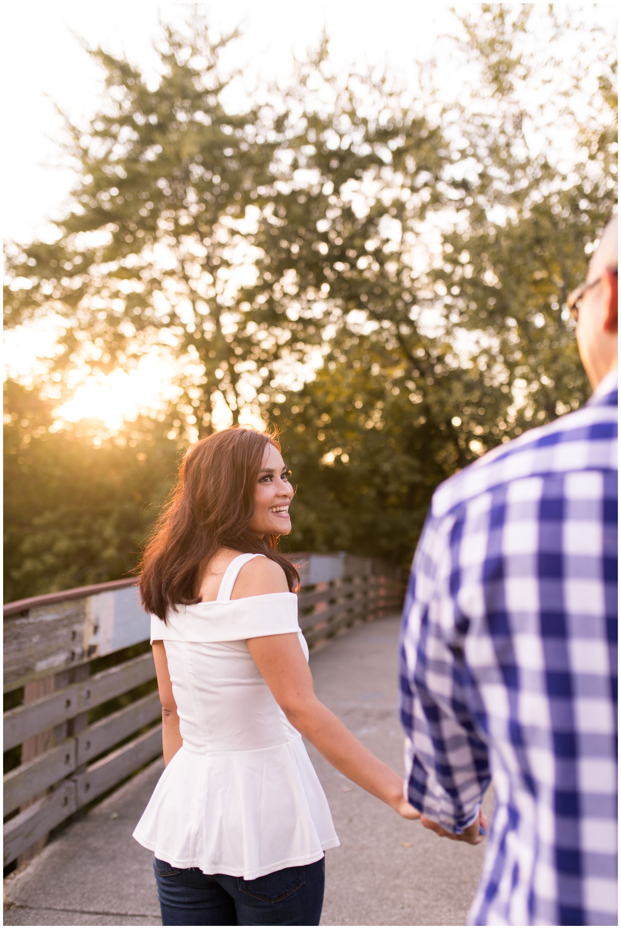 bride leads groom walking toward sunset during Fort Wayne engagement session
