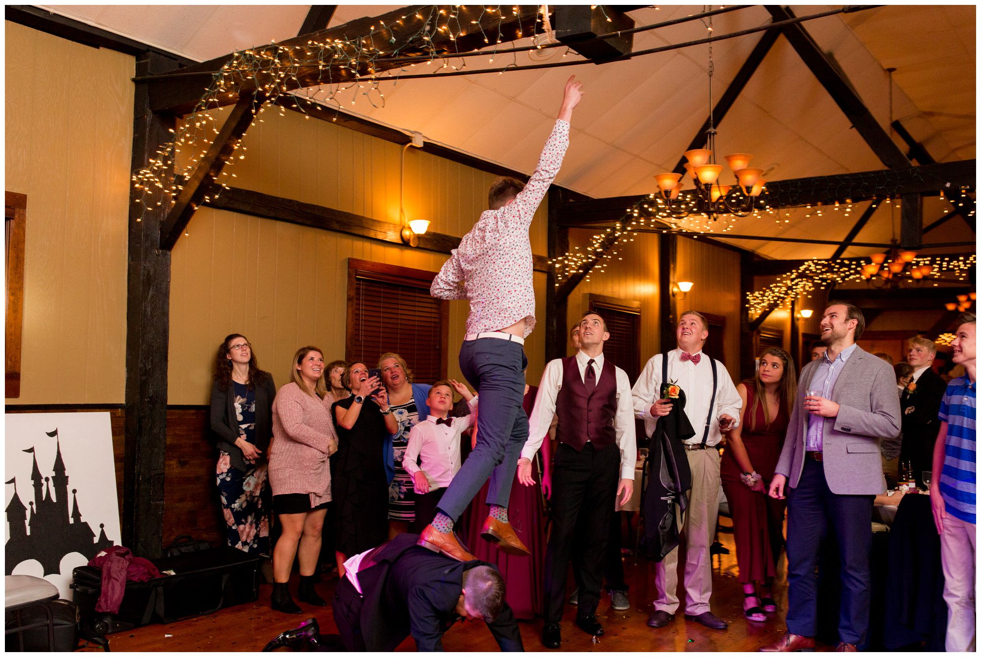 wedding guest jumps up to grab garter stuck on wood beam