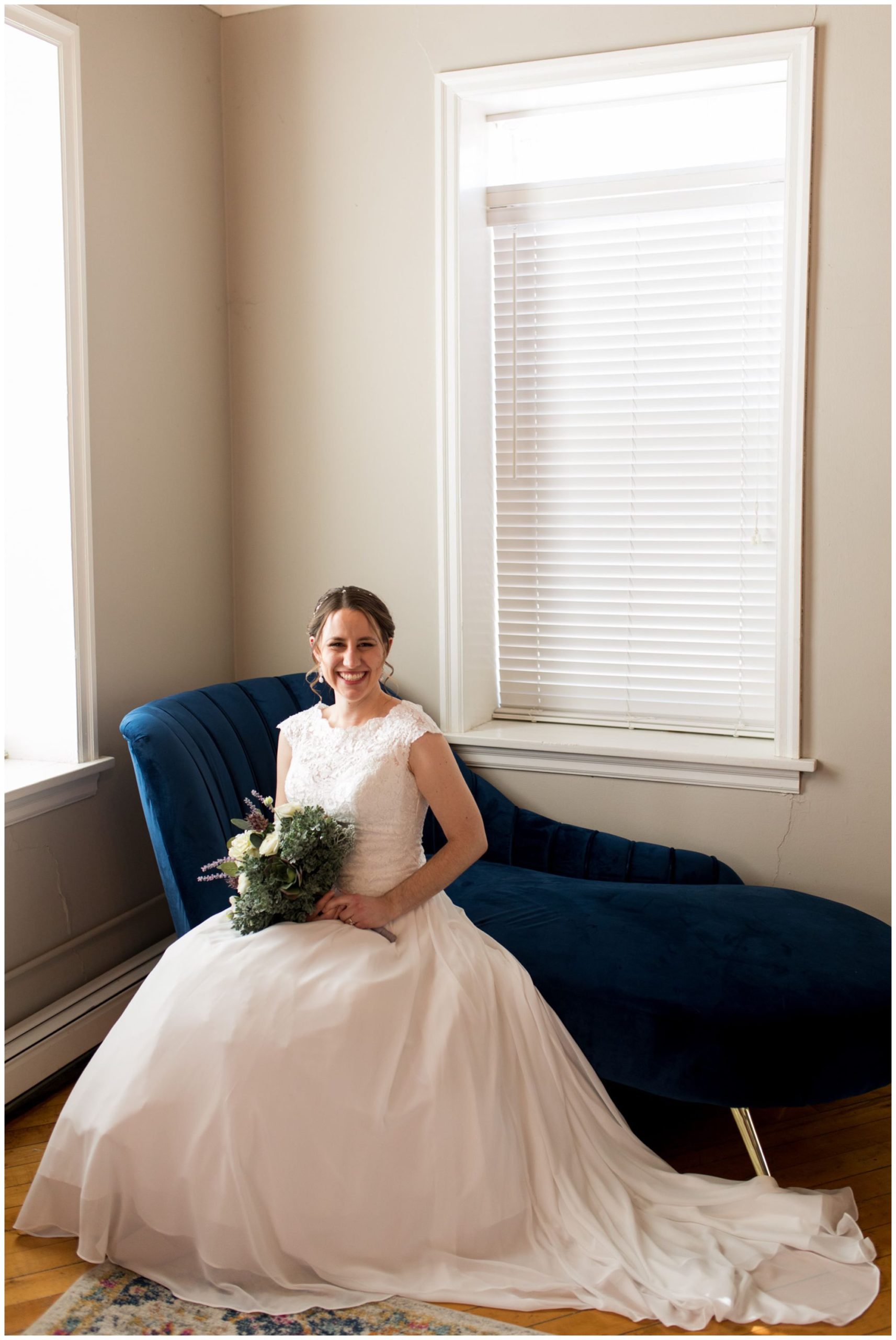 bride sits on chaise in bride's getting ready room at Old Bag Factory in Goshen