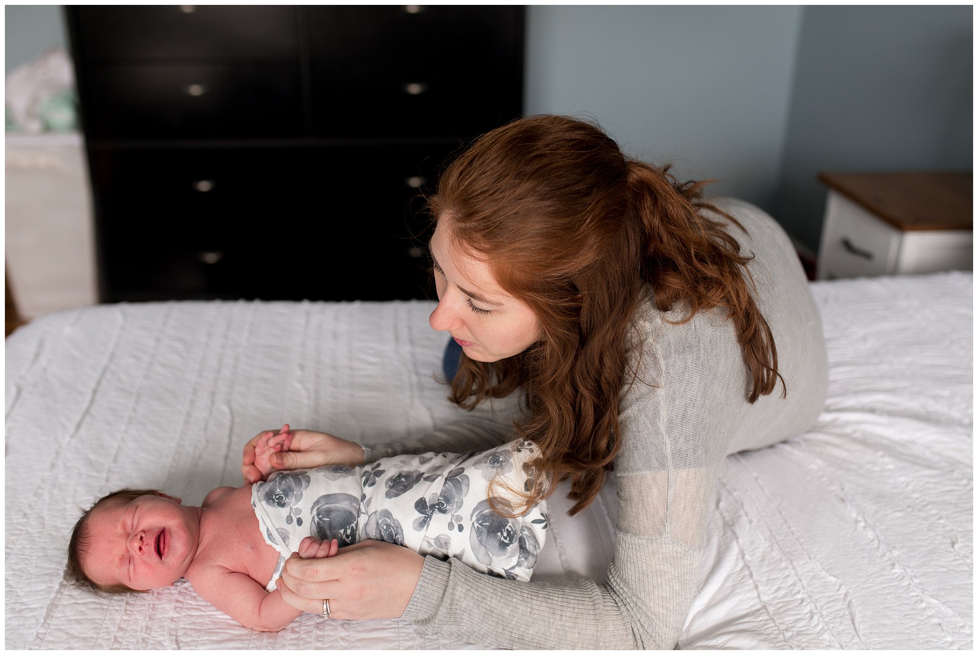 mom lies next to newborn baby on bed during newborn session