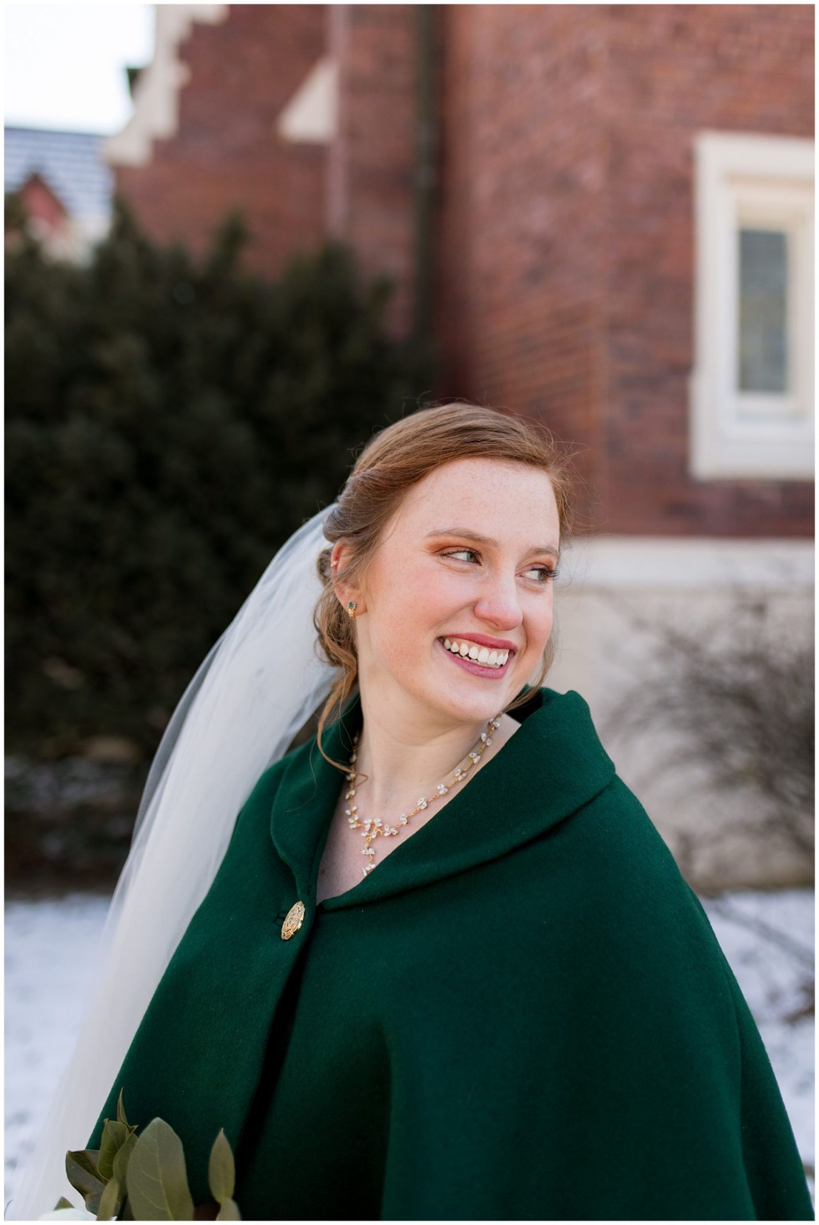 bride looks over shoulder wearing green cape