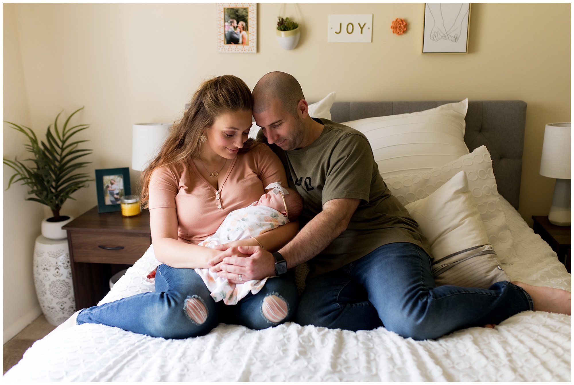 mom and dad hold newborn on bed