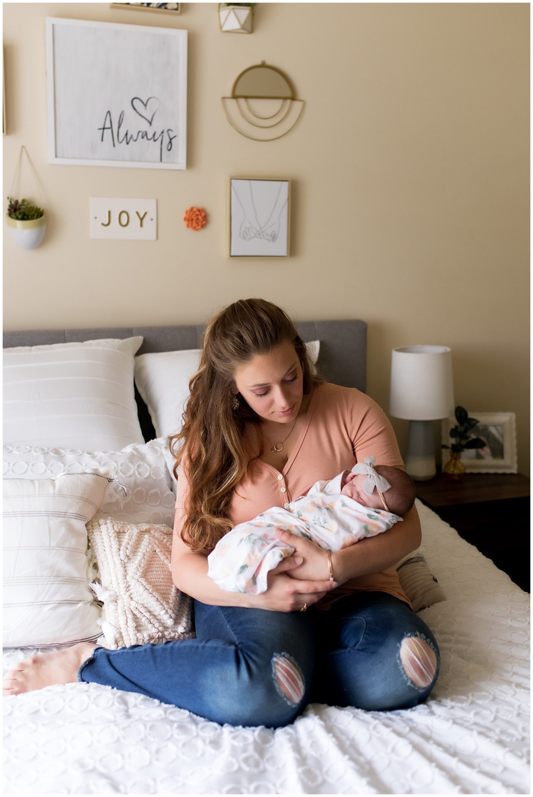 mom holds baby while sitting on bed
