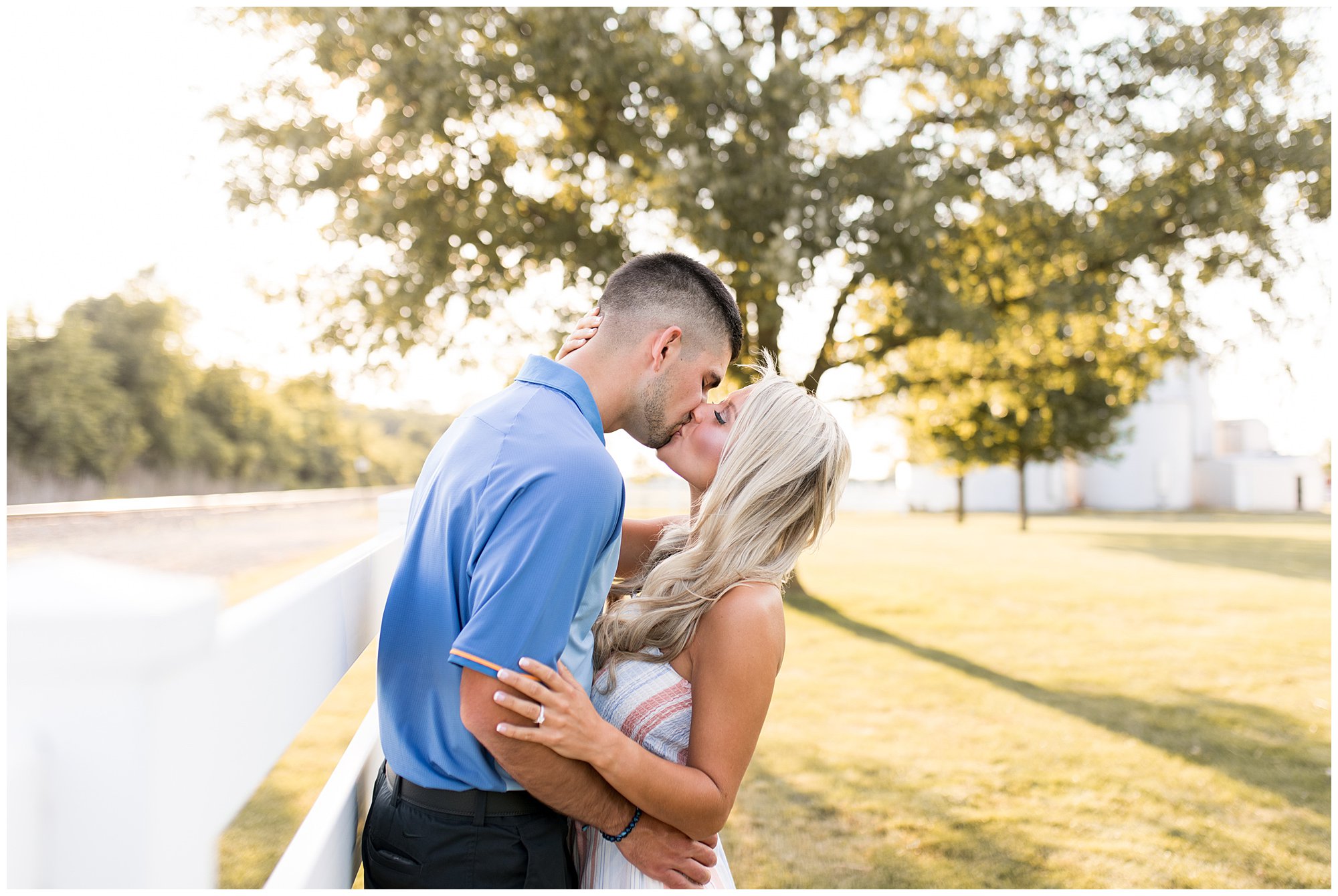 bride and groom kiss against fence line on family farm
