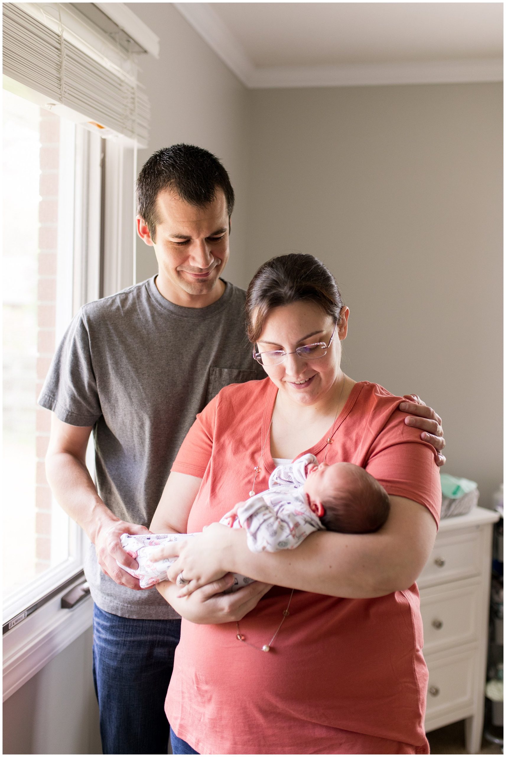 mom holds baby while dad looks onward during newborn session at home