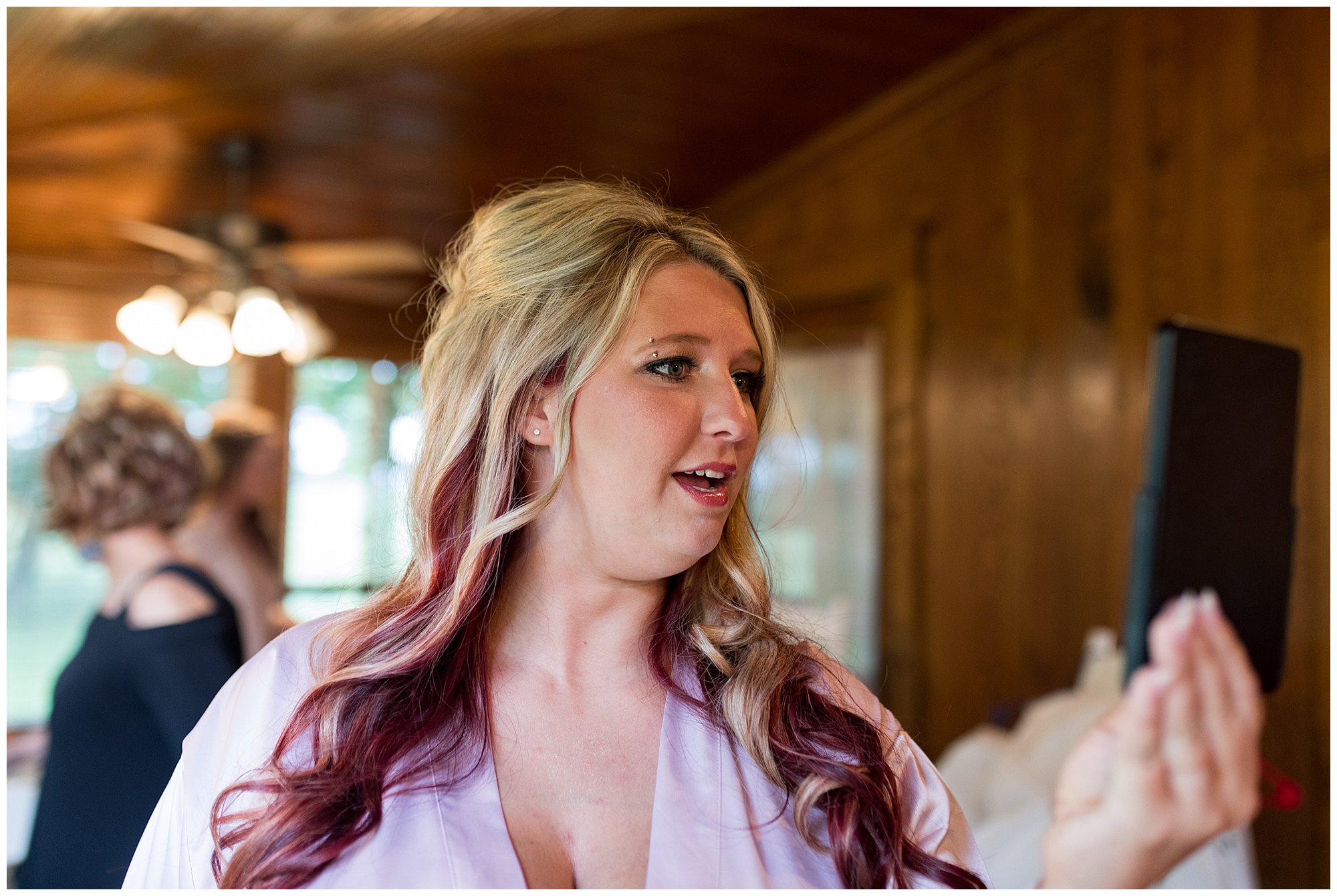 bride looking at herself in mirror after hair and makeup done before wedding at The Old Mill Village in Fremont, Indiana