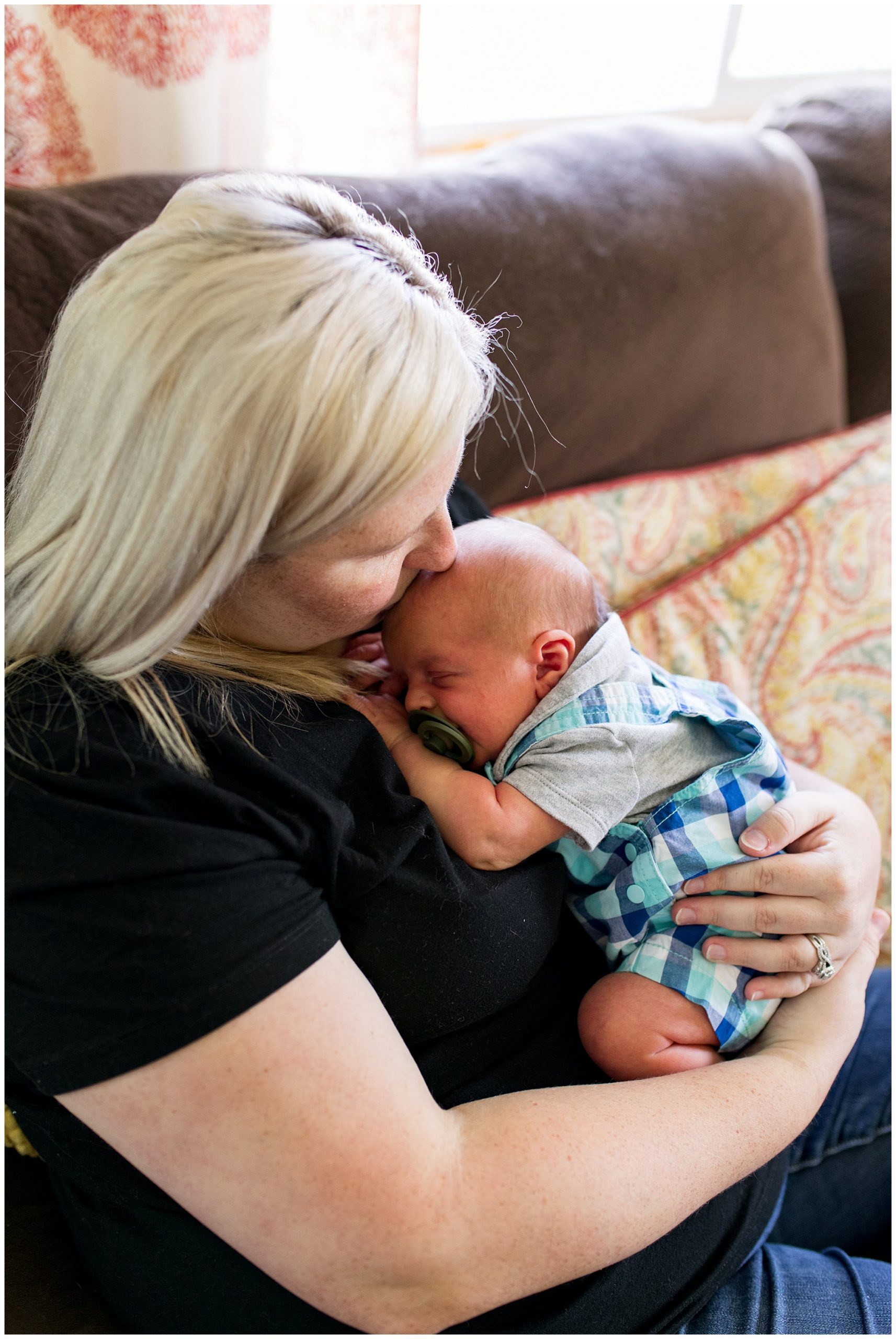mom kisses newborn baby's head during in home newborn session