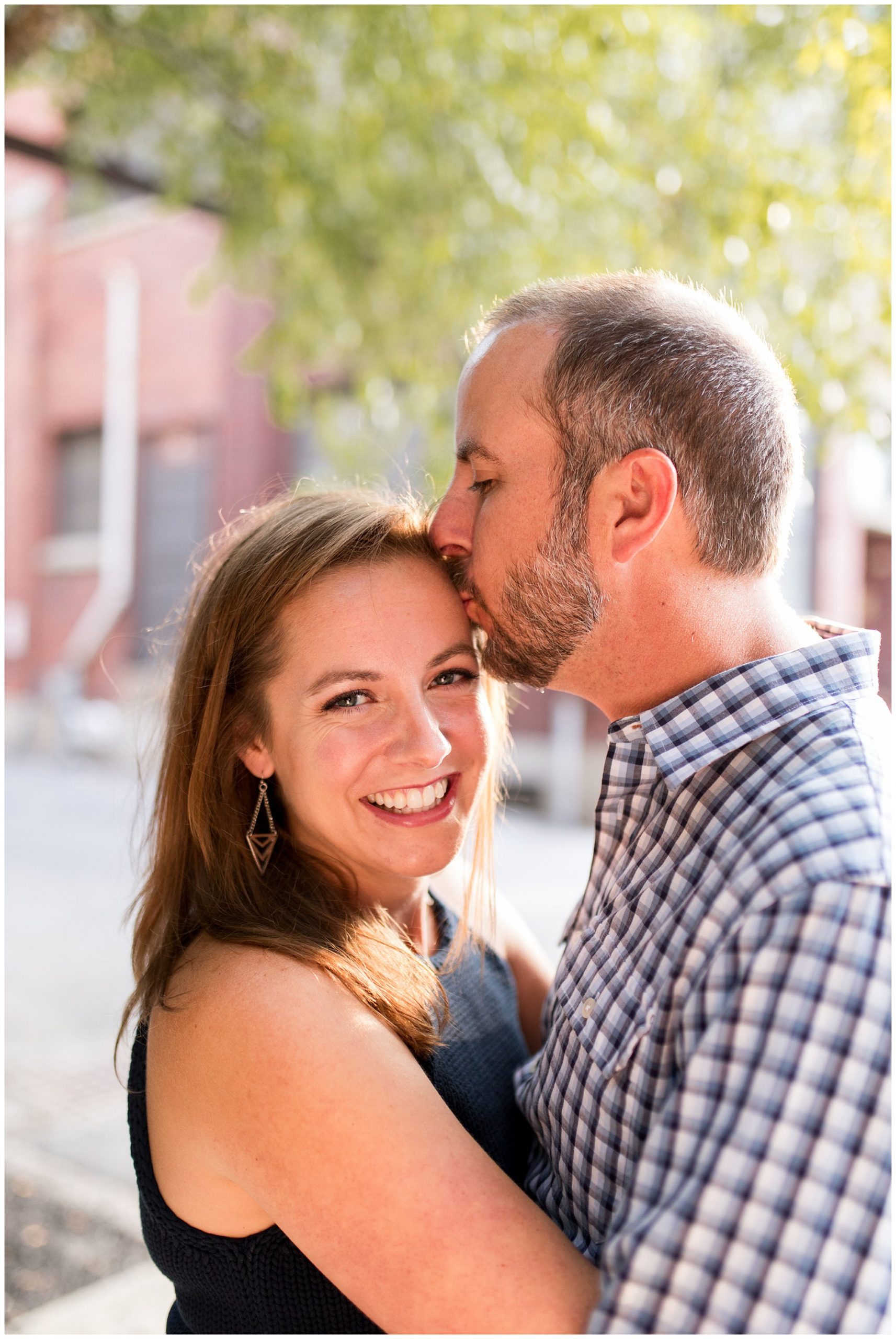 groom kisses bride's forehead during Indianapolis engagement photos at Mass Ave