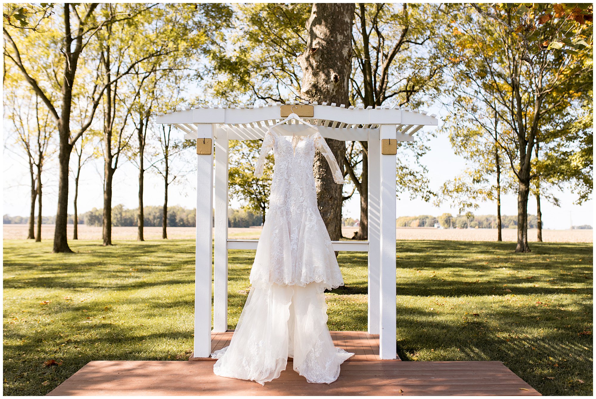 bride's dress hanging on arbor at ceremony site at Legacy Barn in Kokomo