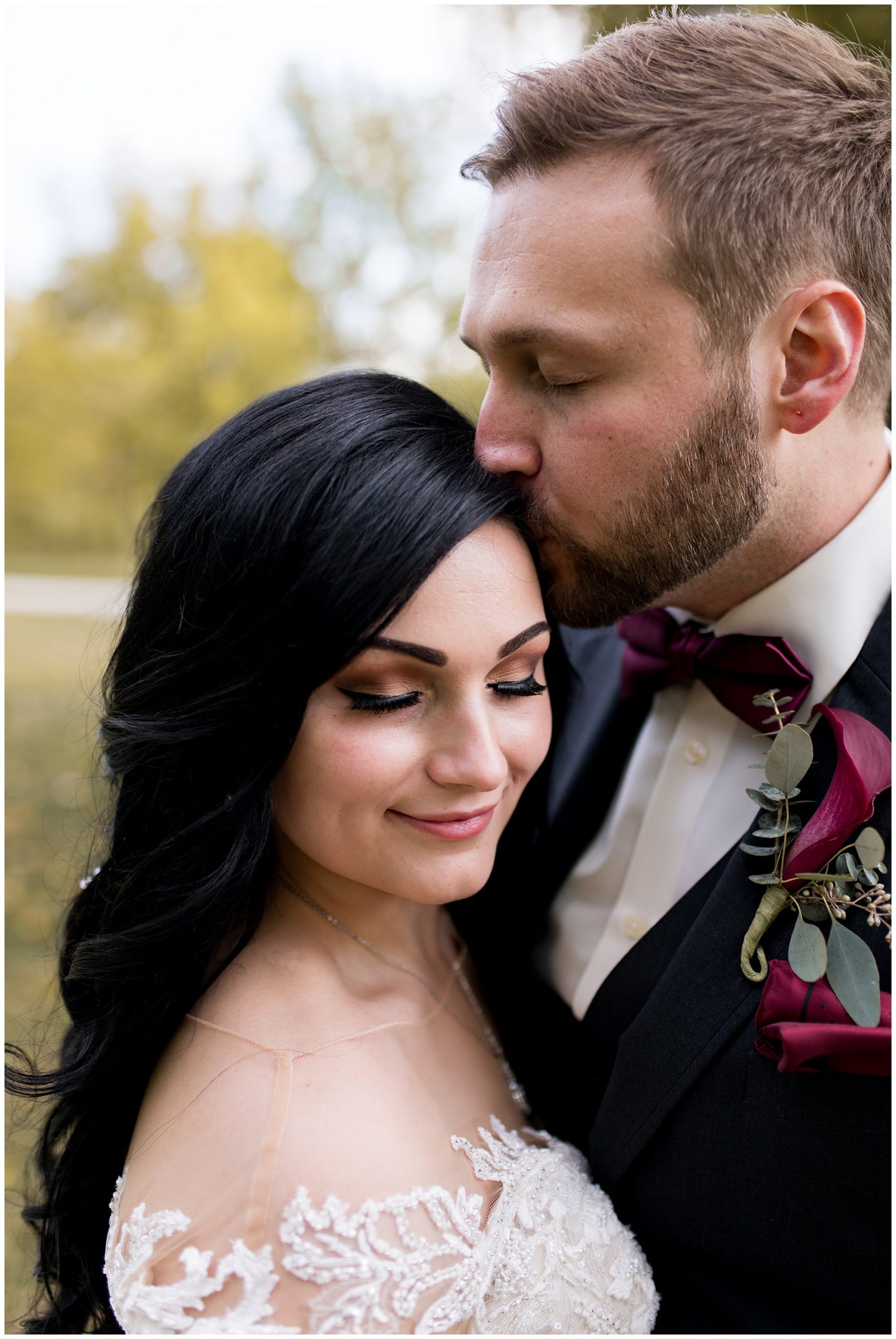 groom kisses bride's forehead during portraits before wedding ceremony at Legacy Barn in Kokomo