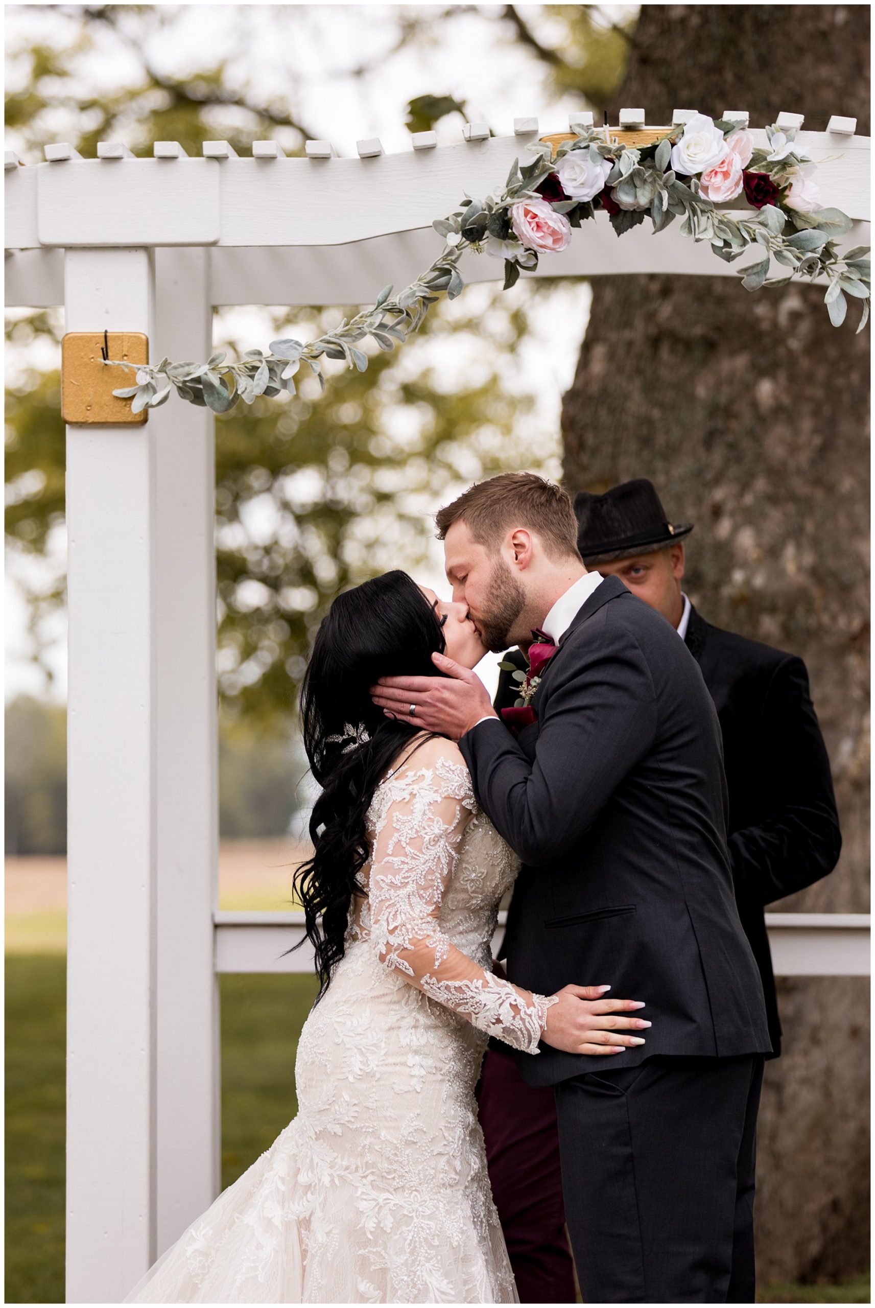 bride and groom first kiss during Legacy Barn wedding ceremony in Kokomo